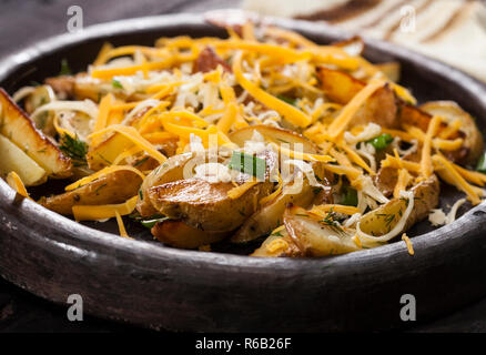 Patate al forno cunei con formaggio, erba cipollina e aneto. In casa vegetale organico vegetariano vegano Spicchi di patate snack alimentare. Foto Stock