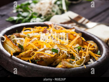 Patate al forno cunei con formaggio, erba cipollina e aneto. In casa vegetale organico vegetariano vegano Spicchi di patate snack alimentare. Foto Stock