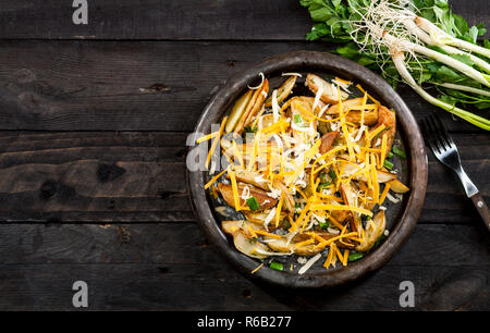 Patate al forno cunei con formaggio, erba cipollina e aneto. In casa vegetale organico vegetariano vegano Spicchi di patate snack alimentare. Vista dall'alto. Foto Stock