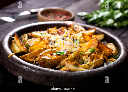 Patate al forno cunei con formaggio, erba cipollina e aneto. In casa vegetale organico vegetariano vegano Spicchi di patate snack alimentare. Foto Stock