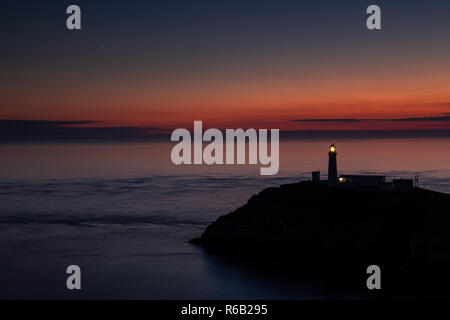 Sud pila faro al tramonto sulla costa di Anglesey, Galles del Nord Foto Stock