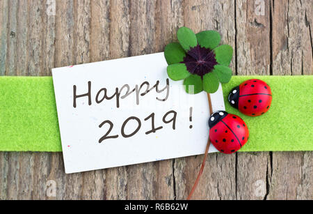Anno Nuovo con scheda leafed trifoglio e ladybugs su sfondo di legno Foto Stock