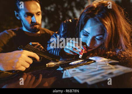 Un criminale di giovane donna tossicodipendente sniffs una pista di cocaina con arrotolato nota. Foto Stock