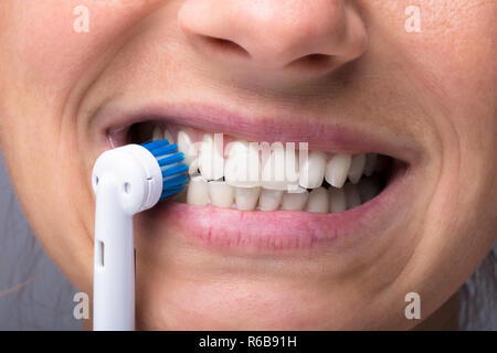 Donna di denti con spazzolino da denti elettrico Foto Stock