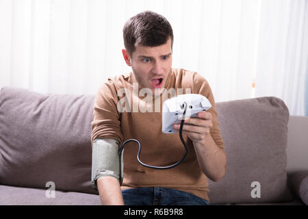 Giovane uomo misurando la sua pressione del sangue Foto Stock