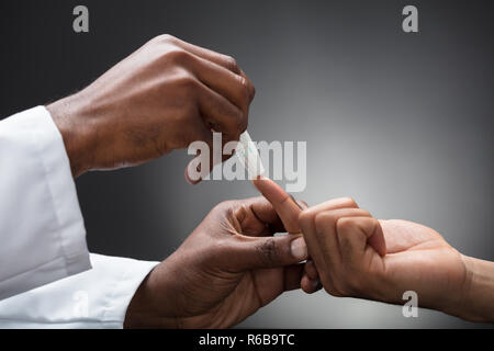 I medici mani con lancetta per controllare il livello di zucchero nel sangue Foto Stock