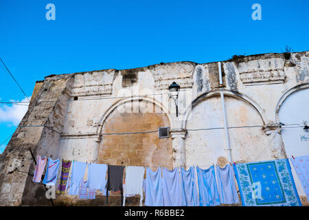 Panni disposti sul filo ad asciugare al sole caldo sotto i resti di una chiesa abbandonata. Foto Stock