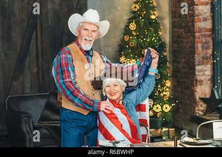 American coppia senior godendo nuovo anno su albero di Natale sfondo Foto Stock