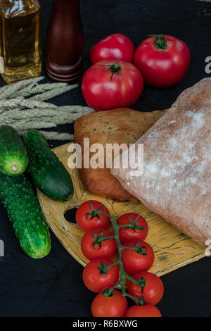 Composizione con verdure fresche e pane. verde cetriolo con pomodoro. in stile country. Foto Stock