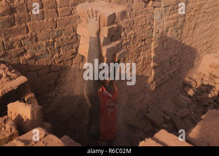 Un lavoro è lavorare in un campo di mattoni con condizioni malsane a Dhaka, nel Bangladesh. Fatiche compresi i bambini lavorano in campi di mattoni fino al tramonto con condizione non sana come il salario non rispondono a standard minimo. Bengalese ha classificato in più rapida crescita paese al mondo come urbanizzazione in rapido aumento. Nonostante di mattone è la chiave i materiali per costruire la struttura di un edificio come grande numero di cantieri di mattoni ha avuto luogo in terre agricole riducendo la produzione agricola. La maggior parte dei cantieri di mattoni utilizzare boschi, carbone per bruciare mattoni crudi come CO2 Emissioni di gas. Foto Stock