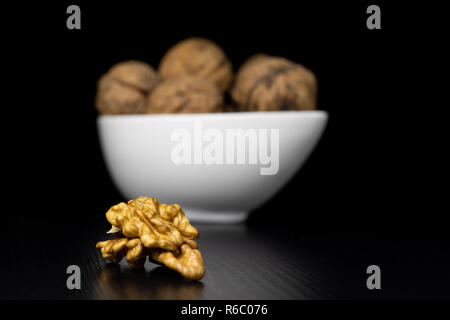 Noci gustose su un nero tavolo da cucina. Ingredienti per preparare la cista in cucina casalinga. Sfondo nero. Foto Stock