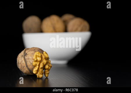Noci gustose su un nero tavolo da cucina. Ingredienti per preparare la cista in cucina casalinga. Sfondo nero. Foto Stock