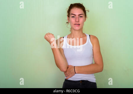 Studio shot della bella ragazza adolescente di mordere il suo labbro con pugno r Foto Stock