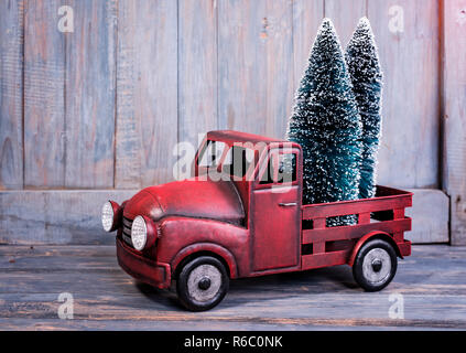 Addobbi natale e auto giocattolo con albero in casa in legno sfondo. Buon Natale concetto. Foto Stock