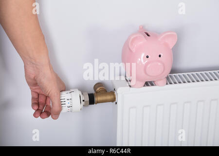 Man mano del termostato di regolazione con il salvadanaio Foto Stock