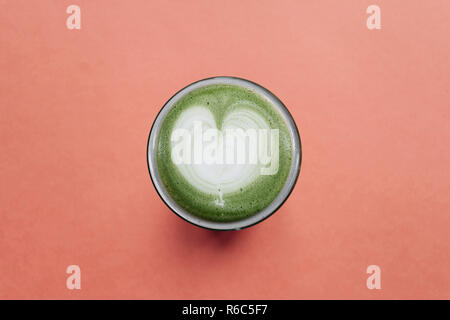Utile fresco Verde matcha latte caffè su uno sfondo di colore rosso. Foto Stock