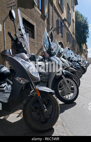 Vista verticale di lotti di ciclomotori Vespa parcheggiata sul lato della strada th in Italia. Foto Stock