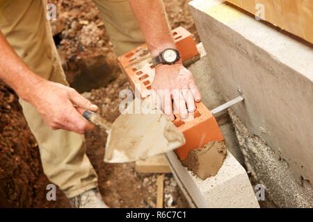 Muratore in mattoni di cementazione in luogo Foto Stock