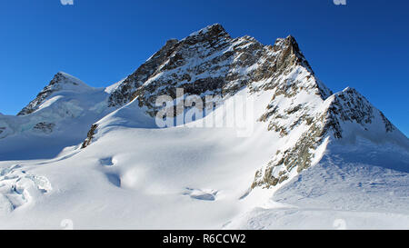 Jungfraujoch, Svizzera - parte superiore dell'Europa. Il monte Jungfrau visto dal pianoro a più alta stazione ferroviaria in Europa sulla soleggiata giornata invernale Foto Stock