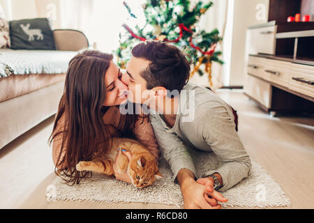 Matura in amore giacenti da albero di Natale e di giocare con il gatto di casa. Felice l'uomo e donna baciare
