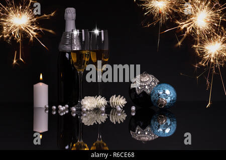 Due bicchieri di vino con champagne, candele e Addobbi Natale su uno sfondo nero con la riflessione. Copia dello spazio. Buon Natale e Felice Anno Nuovo Foto Stock