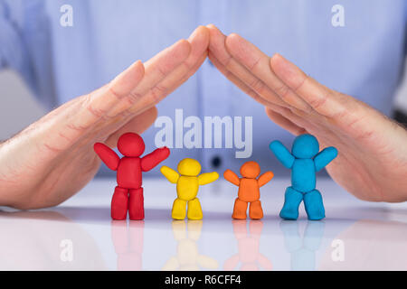 Mano proteggendo la colorata famiglia composta di argilla Foto Stock