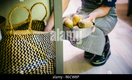 Donna casalinga in cucina. ragazza fuori di prelievo del sacco di patate per la cottura Foto Stock