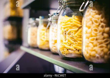 La pasta nel vaso del frullatore. su ripiani di cucina sono diversi tipi di pasta in vasetti di vetro Foto Stock