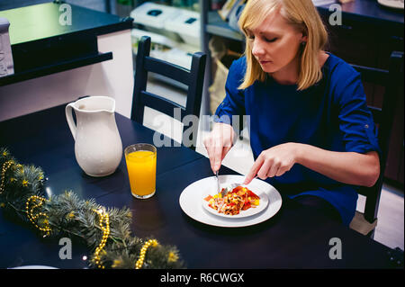 Donna di mangiare cibo fatto in casa, di propria preparazione uovo fritto. La prima colazione per due persone a casa in cucina al tavolo da pranzo Foto Stock