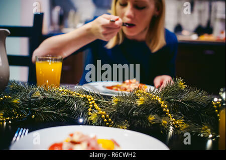 Donna di mangiare cibo fatto in casa, di propria preparazione uovo fritto. La prima colazione per due persone a casa in cucina al tavolo da pranzo Foto Stock