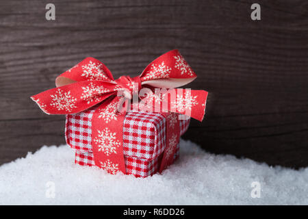 Regalo di natale Scatola sulla neve su sfondo di legno Foto Stock