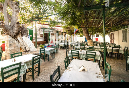 Hydra, Grecia - Ottobre 4th, 2018: una tradizionale taverna greca con legno sedie di verde nel centro della città, Hydra, Grecia. Foto Stock