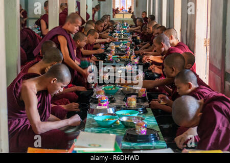 Studente buddista monaci di mangiare il pranzo nella loro sala da pranzo presso il monastero Mahagandayon Foto Stock