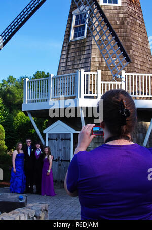 Plainville, CT, Stati Uniti d'America. Giugno 2013. Mom con uno smartphone record felicemente questo evento speciale dei suoi bambini la notte di promenade. Foto Stock