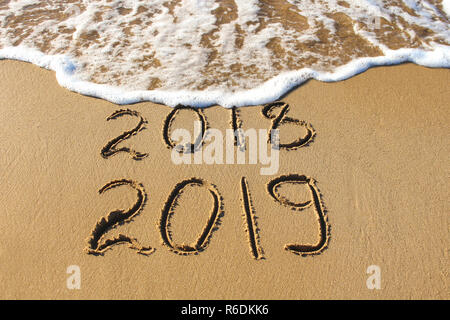 2019, 2018 anni scritto sulla spiaggia di sabbia di mare. Wave lava via 2018. Foto Stock