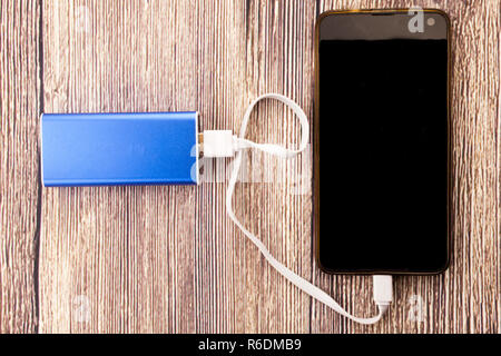 Ricarica del telefono con la banca di energia powerbank. La profondità di campo sulla banca di potenza e cellulare Foto Stock