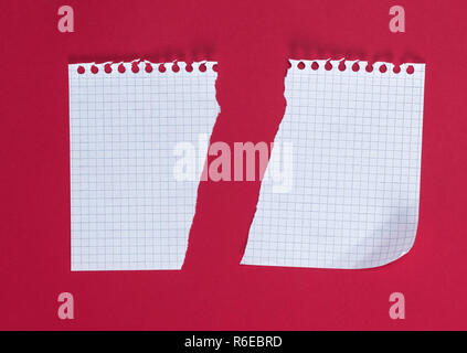 Mezza vuota strappato il foglio bianco in una cella su uno sfondo rosso, close up