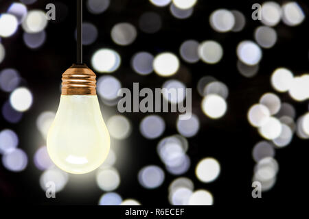 Luce di illuminazione lampadina appesa con colorati sfocate luci di Natale bokeh effetto copia e spazio. Foto Stock