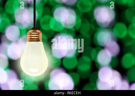 Luce di illuminazione lampadina appesa con colorati sfocate luci di Natale bokeh effetto copia e spazio. Foto Stock