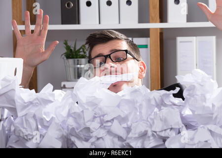 Close-up di imprenditore dietro il mucchio di carta sgualcita Foto Stock