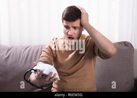 Giovane uomo misurando la sua pressione del sangue Foto Stock