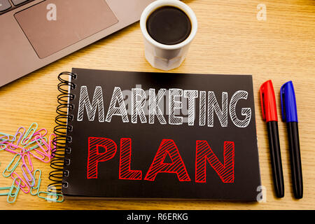 Annuncio della scrittura testo che mostra il piano di marketing. Il concetto di business per la pianificazione della strategia di successo scritto sul libro dei notebook sullo sfondo di legno in ufficio con il caffè per laptop Foto Stock