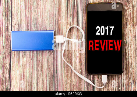 La parola, la scrittura 2017 Recensione. Il concetto di business per la relazione annuale di sintesi scritta su telefono cellulare mobile e power-bank caricabatterie su legno vecchio sfondo di legno Foto Stock
