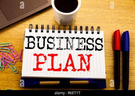 La scrittura a mano didascalia di testo che mostra il piano di Business Planning. Il concetto di business per la preparazione della strategia del progetto scritto sul libro dei notebook sullo sfondo di legno in ufficio con il caffè per laptop Foto Stock