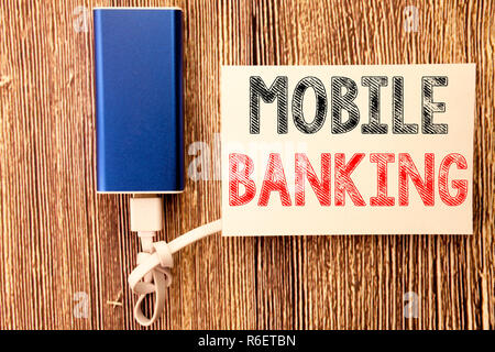 Mano concettuale di scrittura di testo Didascalia ispirazione mostra Mobile Banking. Il concetto di Business di Internet Banking e-bank scritto su una nota adesiva di legno vecchio sfondo di legno con banca di potenza Foto Stock