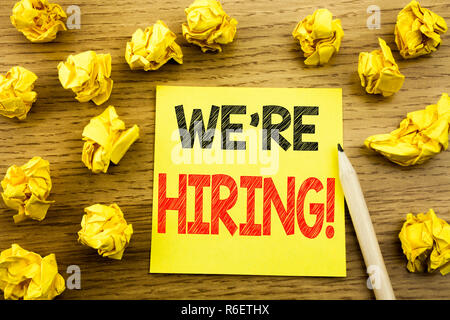 La parola, la scrittura ci sono ora di assunzione. Il concetto di business per il reclutamento di risorse umane scritto su una nota adesiva carta sullo sfondo di legno. Piegate le carte di colore giallo su sfondo Foto Stock