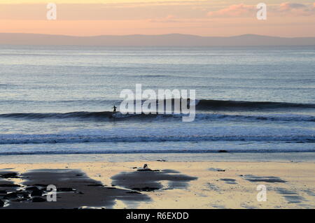 Due surfisti uno su ciascuna delle 2 serie di onde sono in sella allo stesso tempo su un perfetto il reef break nel Galles del Sud. Foto Stock