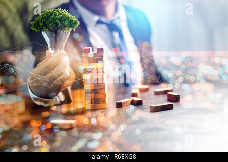 Risparmiare energia e concetto verde, doppia esposizione imprenditore tenendo lampadina con albero verde sulla notte cityscape sfondo, umano è il miglior importan Foto Stock