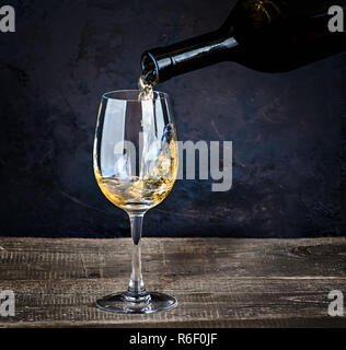 Versare il vino bianco da bottiglia Foto Stock