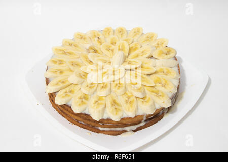 Banana torta biscotto su uno sfondo bianco. Torta dolce con latte condensato salsa. Prodotti da forno Foto Stock